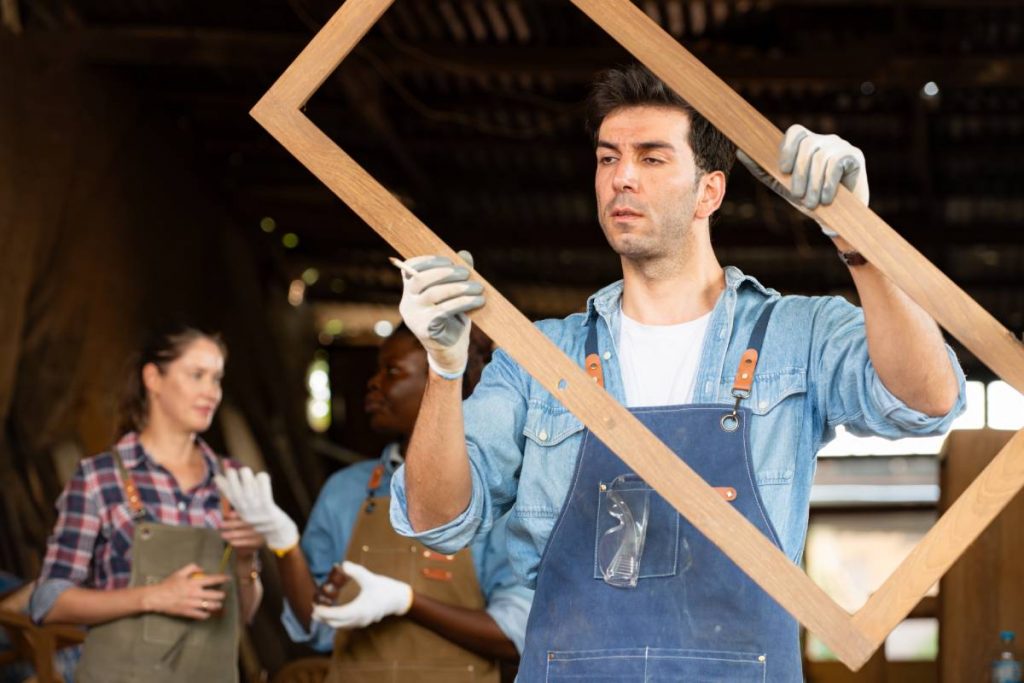 Portrait of carpenter male worker standing in front of colleague in workshop, Eyesight is utilized to ensure accuracy.