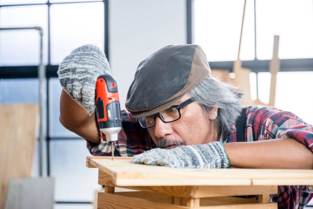 The carpenter is using the tools to work in the wooden studio.